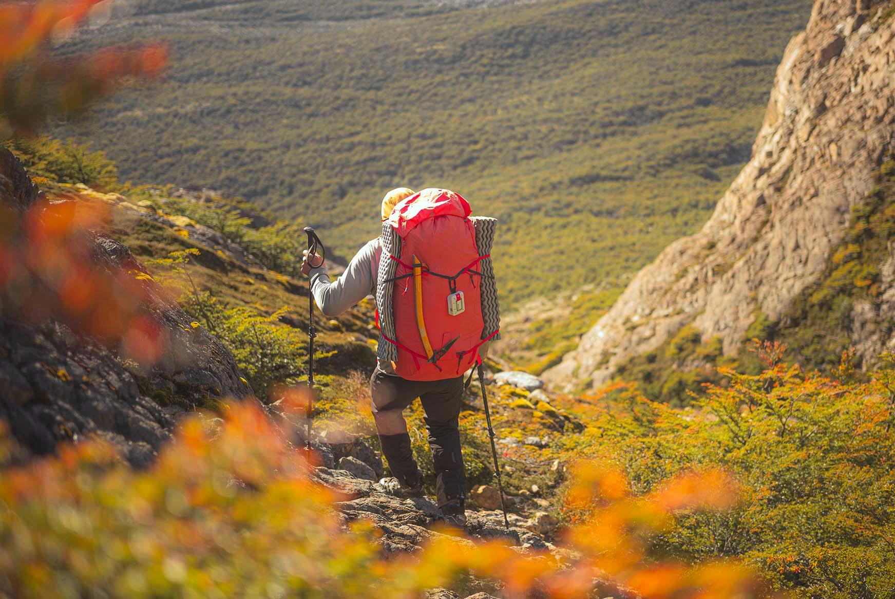 Ein Wanderer geht mit einem ZOLEO am Rucksack einen Berg hinunter
