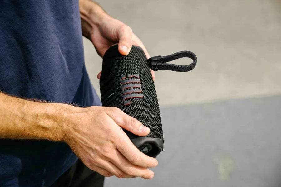 JBL Charge 6 in Schwarz wird mit dem abnehmbaren Tragegurt in der Hand gehalten